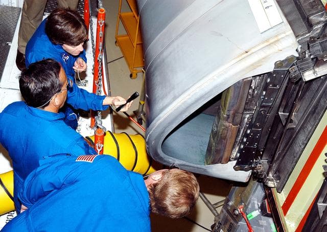 NASA image: KENNEDY SPACE CENTER, FLA. -    In the Orbiter Processing Facility, STS-114 crew members look at the reinforced carbon-carbon panels on the wing of Atlantis. From top to bottom are Commander Eileen Collins and Mission Specialists Charles Camarda and Andrew Thomas.  The STS-114 crew is at KSC to take part in crew equipment and orbiter familiarization.