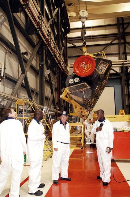 NASA image: KENNEDY SPACE CENTER, FLA. - In the Orbiter Processing Facility, workers discuss the next step in moving the orbital maneuvering system (OMS) pod behind them.  The OMS pod will be installed on Atlantis.  Two OMS pods are attached to the upper aft fuselage left and right sides. Fabricated primarily of graphite epoxy composite and aluminum, each pod is 21.8 feet long and 11.37 feet wide at its aft end and 8.41 feet wide at its forward end, with a surface area of approximately 435 square feet. Each pod houses the Reaction Control System propulsion components used for inflight maneuvering and is attached to the aft fuselage with 11 bolts.