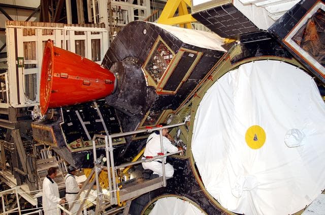 NASA image: KENNEDY SPACE CENTER, FLA. - In the Orbiter Processing Facility, technicians make adjustments to the orbital maneuvering system (OMS) pod being installed on Atlantis.   The OMS pod is one of two that are attached to the upper aft fuselage left and right sides. Fabricated primarily of graphite epoxy composite and aluminum, each pod is 21.8 feet long and 11.37 feet wide at its aft end and 8.41 feet wide at its forward end, with a surface area of approximately 435 square feet. Each pod houses the Reaction Control System propulsion components used for inflight maneuvering and is attached to the aft fuselage with 11 bolts.