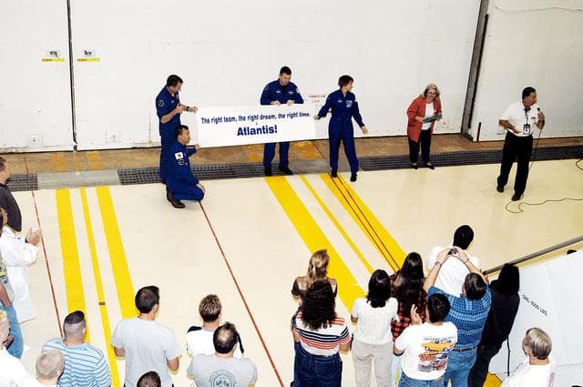 NASA image: KENNEDY SPACE CENTER, FLA. - Members of the STS-114 crew hold a sign presented to  workers in the Orbiter Processing Facility.  From left are  Mission Specialists Soichi Noguchi (kneeling) and Stephen Robinson, Pilot James Kelly and Mission Commander Eileen Collins. Noguchi is with the Japan Aerospace Exploration Agency, JAXA.  The STS-114 crew is at KSC to take part in crew equipment and orbiter familiarization.