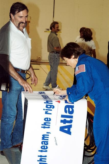 NASA image: KENNEDY SPACE CENTER, FLA. - STS-114 Mission Specialist Wendy Lawrence autographs the sign presented to  workers in the Orbiter Processing Facility. Lawrence is a new addition to the crew.  The STS-114 crew is at KSC to take part in crew equipment and orbiter familiarization.