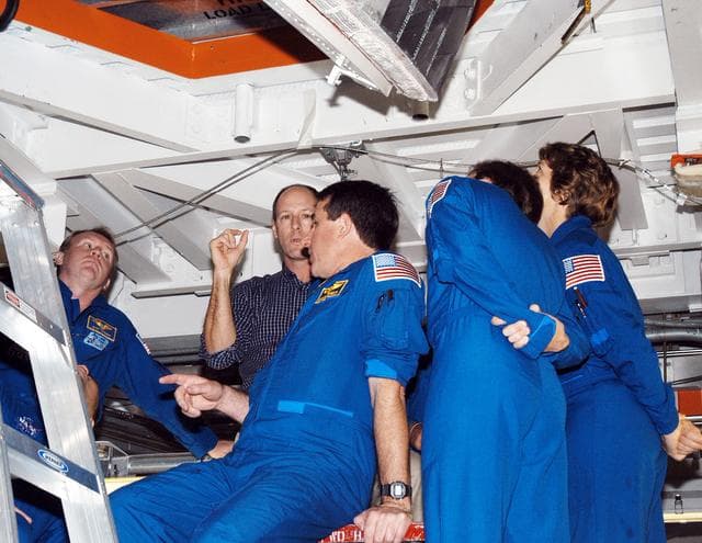 KENNEDY SPACE CENTER, FLA. - In the Orbiter Processing Facility, members of the STS-114 crew look up at the payload bay of orbiter Atlantis.  From left (in flight suits) are Mission Specialists Andrew Thomas, Stephen Robinson and Charles Camarda, and Mission Commander Eileen Collins. The STS-114 crew is at KSC to take part in crew equipment and orbiter familiarization.