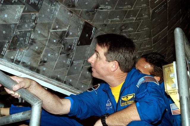 NASA image: KENNEDY SPACE CENTER, FLA. - In the Orbiter Processing Facility, STS-114 Mission Specialist Stephen Robinson looks closely at the tiles underneath the orbiter Atlantis.  The STS-114 crew is at KSC to take part in crew equipment and orbiter familiarization.