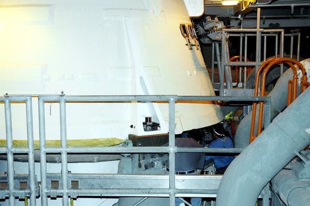 NASA image: KENNEDY SPACE CENTER, FLA. -  The camera installed on the aft skirt of a solid rocket booster is seen here, framed by the railing.  The installation is in preparation for a vibration test of the Mobile Launcher Platform with SRBs and external tank mounted.  The MLP will roll from one bay to another in the Vehicle Assembly Building.