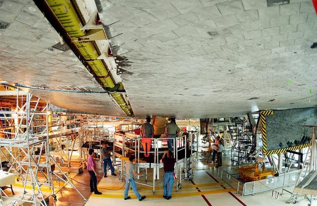 NASA image: KENNEDY SPACE CENTER, FLA. -  Workers in the Orbiter Processing Facility oversee installation of the liquid oxygen feedline for the 17-inch disconnect on the orbiter Discovery.  The 17-inch liquid oxygen and liquid hydrogen disconnects provide the propellant feed interface from the external tank to the orbiter main propulsion system and the three Shuttle main engines.