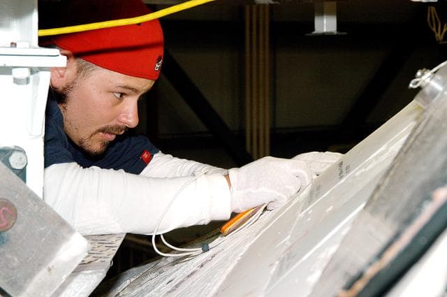 NASA image: KENNEDY SPACE CENTER, FLA. - In the Orbiter Processing Facility, United Space Alliance technician Chris Moore performs gap tests on the tiles of the nose of orbiter Atlantis as part of return-to-flight activities.  Atlantis is scheduled for mission STS-114, a return-to-flight test mission to the International Space Station.