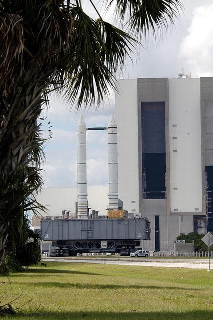 NASA image: KENNEDY SPACE CENTER, FLA. -  Mobile Launcher Platform (MLP) number 3 and a set of twin solid rocket boosters, atop the crawler-transporter, crawls away from the Vehicle Assembly Building in support of the second engineering analysis vibration test on the crawler and MLP. The crawler is moving at various speeds up to 1 mph in an effort to achieve vibration data gathering goals as it leaves the VAB, travels toward Launch Pad 39A and then returns.  The boosters are braced at the top for stability.  The primary purpose of these rollout tests is to gather data to develop future maintenance requirements on the transport equipment and the flight hardware. Various parts of the MLP and crawler transporter have been instrumented with vibration data collection equipment.
