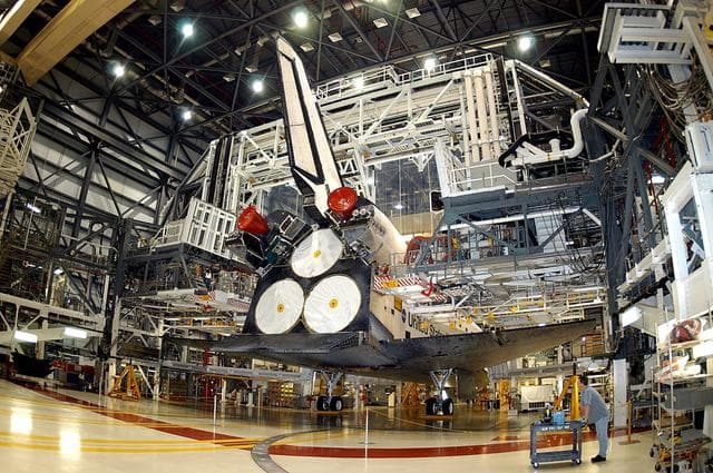 NASA image: KENNEDY SPACE CENTER, FLA. - The Space Shuttle orbiter Atlantis awaits a tow from the Orbiter Processing Facility (OPF) to the Vehicle Assembly Building (VAB). The move will allow work to be performed in the OPF that can only be accomplished while the bay is empty. Work scheduled in the processing facility includes annual validation of the bay's cranes, work platforms, lifting mechanisms, and jack stands. Atlantis will remain in the VAB for about 10 days, then return to the OPF as work resumes to prepare it for launch in September 2004 on the first return-to-flight mission, STS-114.
