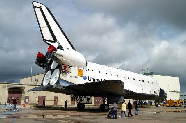 NASA image: KENNEDY SPACE CENTER, FLA. - Workers monitor the Space Shuttle orbiter Atlantis as it is towed from the Orbiter Processing Facility (OPF) to the Vehicle Assembly Building (VAB). The move will allow work to be performed in the OPF that can only be accomplished while the bay is empty. Work scheduled in the processing facility includes annual validation of the bay's cranes, work platforms, lifting mechanisms, and jack stands. Atlantis will remain in the VAB for about 10 days, then return to the OPF as work resumes to prepare it for launch in September 2004 on the first return-to-flight mission, STS-114.