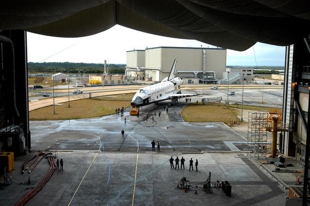 NASA image: KENNEDY SPACE CENTER, FLA. - The Space Shuttle orbiter Atlantis approaches high bay 4 of the Vehicle Assembly Building (VAB).  It was towed from the Orbiter Processing Facility (OPF) to allow work to be performed in the bay that can only be accomplished while it is empty. Work scheduled in the processing facility includes annual validation of the bay's cranes, work platforms, lifting mechanisms, and jack stands. Atlantis will remain in the VAB for about 10 days, then return to the OPF as work resumes to prepare it for launch in September 2004 on the first return-to-flight mission, STS-114.