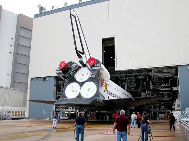 NASA image: KENNEDY SPACE CENTER, FLA. - The Space Shuttle orbiter Atlantis backs out of the Orbiter Processing Facility (OPF) for its move to the Vehicle Assembly Building (VAB). The move will allow work to be performed in the OPF that can only be accomplished while the bay is empty. Work scheduled in the processing facility includes annual validation of the bay's cranes, work platforms, lifting mechanisms, and jack stands. Atlantis will remain in the VAB for about 10 days, then return to the OPF as work resumes to prepare it for launch in September 2004 on the first return-to-flight mission, STS-114.
