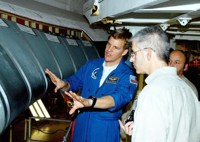 NASA image: KENNEDY SPACE CENTER, FLA. -  In the Orbiter Processing Facility, astronaut Scott E. Parazynski discusses the Reinforced Carbon Carbon panels used on the leading edge of the wing of the orbiters.  With him are engineers from around the Agency who are working on improving the RCC panels used on the wing leading edge. The gray carbon composite RCC panels have sufficient strength to withstand the aerodynamic forces experienced during launch and reentry, which can reach as high as 800 pounds per square foot.  The operating range of RCC is from minus 250º F to about 3,000º F, the temperature produced by friction with the atmosphere during reentry.