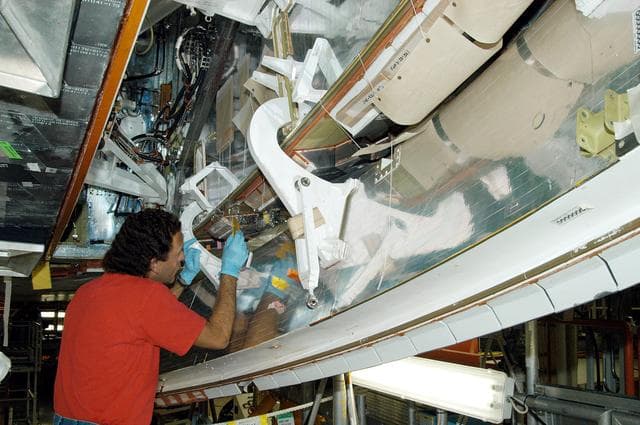 NASA image: KENNEDY SPACE CENTER, FLA. -  In the Orbiter Processing Facility, KSC employee Gene Peavler works in the wheel area on the orbiter Discovery.  The vehicle has undergone Orbiter Major Modifications in the past year.  Discovery is scheduled to fly on mission STS-121 to the International Space Station.
