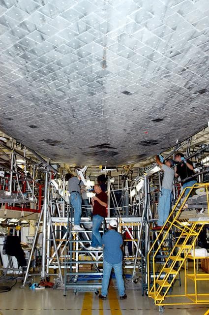 NASA image: KENNEDY SPACE CENTER, FLA. -  In the Orbiter Processing Facility, KSC technicians work on the underbody of the orbiter Discovery.  The vehicle has undergone Orbiter Major Modifications in the past year.  Discovery is scheduled to fly on mission STS-121 to the International Space Station.