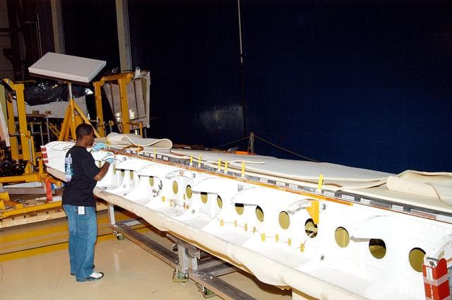 NASA image: KENNEDY SPACE CENTER, FLA. -  In the Orbiter Processing Facility, KSC employee Duane Williams prepares the blanket insulation to be installed on the body flap on orbiter Discovery.  The blankets are part of the Orbiter Thermal Protection System, thermal shields to protect against temperatures as high as 3,000° Fahrenheit, which are produced during descent for landing. Discovery is scheduled to fly on mission STS-121 to the International Space Station.