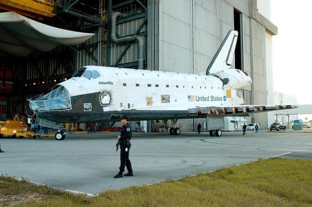 NASA image: KENNEDY SPACE CENTER, FLA. -- The orbiter Atlantis  is backed away from the Vehicle Assembly Building for transfer back to the Orbiter Processing Facility.  Atlantis spent 10 days in the VAB to allow work to be performed in the OPF that can only be accomplished while the bay is empty. Work included annual validation of the bay's cranes, work platforms, lifting mechanisms and jack stands.  Work resumes to prepare Atlantis for launch in September 2004 on the first return-to-flight mission, STS-114.