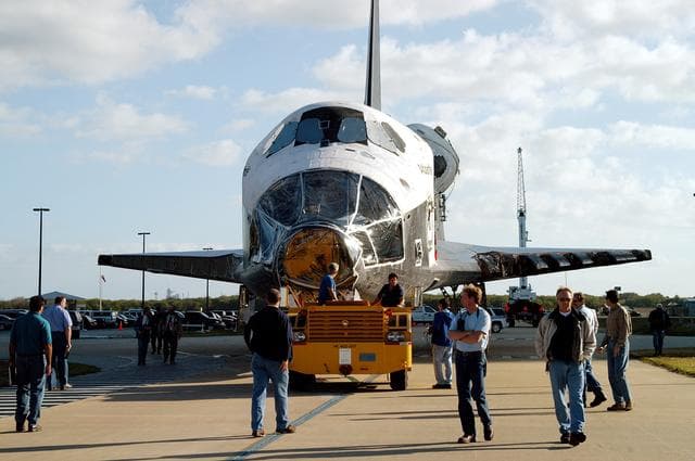NASA image: KENNEDY SPACE CENTER, FLA. -  Workers accompany the orbiter Atlantis as it is towed back to the Orbiter Processing Facility after spending 10 days in the Vehicle Assembly Building.  The hiatus in the VAB allowed work to be performed in the OPF that can only be accomplished while the bay is empty. Work included annual validation of the bay's cranes, work platforms, lifting mechanisms and jack stands.  Work resumes to prepare Atlantis for launch in September 2004 on the first return-to-flight mission, STS-114.