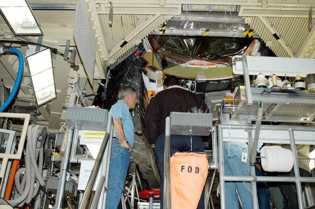 NASA image: KENNEDY SPACE CENTER, FLA. -- NASA Deputy Associate Administrator for Space Station and Shuttle Programs Michael Kostelnik (left) discusses some of the working parts inside the nose of Shuttle Discovery in Orbiter Processing Facility Bay 3 with a United Space Alliance (USA) technician (back to camera).  NASA and USA Space Shuttle program management are participating in a leadership workday.  The day is intended to provide management with an in-depth, hands-on look at Shuttle processing activities at KSC.