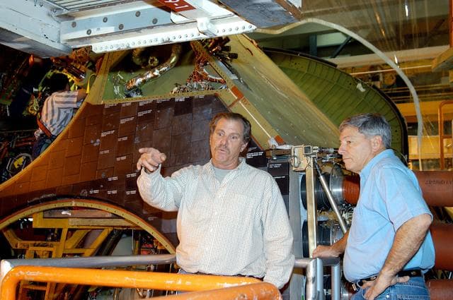 NASA image: KENNEDY SPACE CENTER, FLA. -- NASA Deputy Associate Administrator for Space Station and Shuttle Programs Michael Kostelnik (right) discusses a speed brake on Shuttle Discovery in Orbiter Processing Facility Bay 3 with a United Space Alliance (USA) technician (left).  NASA and USA Space Shuttle program management are participating in a leadership workday.  The day is intended to provide management with an in-depth, hands-on look at Shuttle processing activities at KSC.