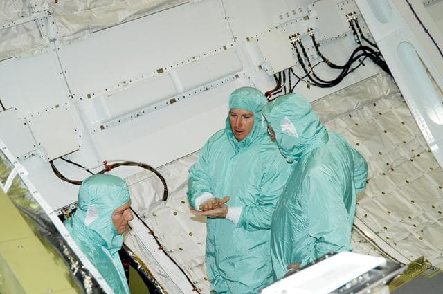 NASA image: KENNEDY SPACE CENTER, FLA. -- In Orbiter Processing Facility Bay 1, NASA Deputy Associate Administrator for Space Station and Shuttle Programs Michael Kostelnik (left) and United Space Alliance (USA) Vice President and Space Shuttle Program Manager Howard DeCastro (right) are briefed by a USA technician (center) on Shuttle processing in the payload bay of orbiter Atlantis.  NASA and USA Space Shuttle program management are participating in a leadership workday.  The day is intended to provide management with an in-depth, hands-on look at Shuttle processing activities at KSC.