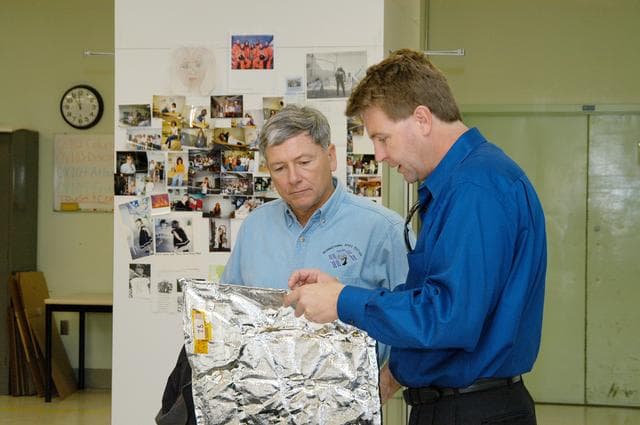 NASA image: KENNEDY SPACE CENTER, FLA. -- United Space Alliance (USA) Manager of the Thermal Protection System (TPS) Facility Martin Wilson (right) briefs NASA Deputy Associate Administrator for Space Station and Shuttle Programs Michael Kostelnik (left) on the properties of a thermal blanket used in the Shuttle's TPS.  NASA and USA Space Shuttle program management are participating in a leadership workday.  The day is intended to provide management with an in-depth, hands-on look at Shuttle processing activities at KSC.