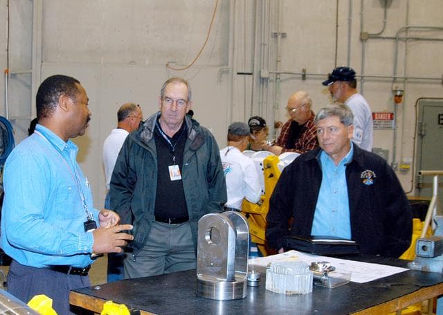 NASA image: KENNEDY SPACE CENTER, FLA. -- From left, a United Space Alliance (USA) technician discusses aspects of Shuttle processing performed in the Solid Rocket Booster (SRB) Assembly and Refurbishment Facility (ARF) with USA Vice President and Space Shuttle Program Manager Howard DeCastro and NASA Deputy Associate Administrator for Space Station and Shuttle Programs Michael Kostelnik.  NASA and USA Space Shuttle program management are participating in a leadership workday.  The day is intended to provide management with an in-depth, hands-on look at Shuttle processing activities at KSC.