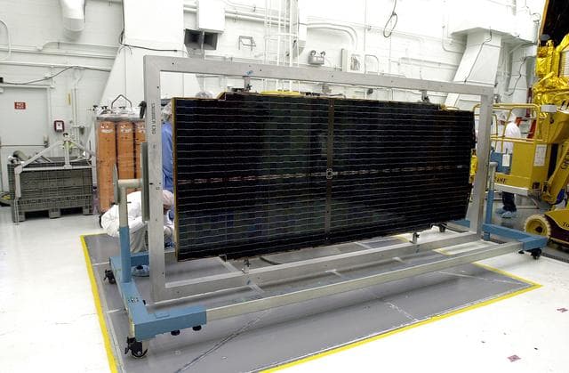 NASA image: VANDENBERG AFB, CALIF. - Workers in the NASA spacecraft processing facility on North Vandenberg Air Force Base work on a solar array panel to be installed on the Gravity Probe B spacecraft.  Installing each array is a 3-day process and includes a functional deployment test.  The Gravity Probe B mission is a relativity experiment developed by NASA’s Marshall Space Flight Center, Stanford University and Lockheed Martin.  The spacecraft will test two extraordinary predictions of Albert Einstein’s general theory of relativity that he advanced in 1916: the geodetic effect (how space and time are warped by the presence of the Earth) and frame dragging (how Earth’s rotation drags space and time around with it).  Gravity Probe B consists of four sophisticated gyroscopes that will provide an almost perfect space-time reference system.  The mission will look in a precision manner for tiny changes in the direction of spin.