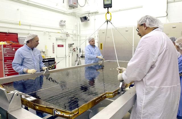 NASA image: VANDENBERG AFB, CALIF. - Workers in the NASA spacecraft processing facility on North Vandenberg Air Force Base attach supports to a solar array panel to be lifted and  installed on the Gravity Probe B spacecraft.  Installing each array is a 3-day process and includes a functional deployment test.  The Gravity Probe B mission is a relativity experiment developed by NASA’s Marshall Space Flight Center, Stanford University and Lockheed Martin.  The spacecraft will test two extraordinary predictions of Albert Einstein’s general theory of relativity that he advanced in 1916: the geodetic effect (how space and time are warped by the presence of the Earth) and frame dragging (how Earth’s rotation drags space and time around with it).  Gravity Probe B consists of four sophisticated gyroscopes that will provide an almost perfect space-time reference system.  The mission will look in a precision manner for tiny changes in the direction of spin.