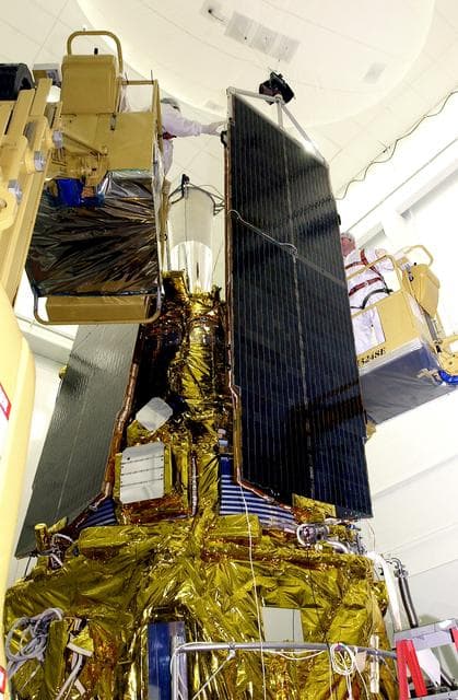 NASA image: VANDENBERG AFB, CALIF. -  In the NASA spacecraft processing facility on North Vandenberg Air Force Base, workers prepare to attach the top of a solar array panel onto the Gravity Probe B spacecraft.  Installing each array is a 3-day process and includes a functional deployment test.  The Gravity Probe B mission is a relativity experiment developed by NASA’s Marshall Space Flight Center, Stanford University and Lockheed Martin.  The spacecraft will test two extraordinary predictions of Albert Einstein’s general theory of relativity that he advanced in 1916: the geodetic effect (how space and time are warped by the presence of the Earth) and frame dragging (how Earth’s rotation drags space and time around with it).  Gravity Probe B consists of four sophisticated gyroscopes that will provide an almost perfect space-time reference system.  The mission will look in a precision manner for tiny changes in the direction of spin.