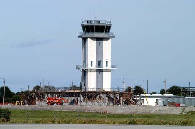 NASA image: KENNEDY SPACE CENTER, FLA. -- A new control tower is nearing completion at the KSC Shuttle Landing Facility.  It will replace the old tower in use since 1987.   The old tower stands only 20 feet above the runway surface, too low to see the launch pads to the east. During nighttime landing operations, those inside the tower have been hindered by the eight-billion candlepower xenon lights that illuminate the runway.  The new control tower is built atop an existing mound, rising nearly 100 feet over the midpoint of the runway.  The height gives controllers a spectacular 360-degree view of NASA-KSC and northern Brevard County. The new facility will also replace the SLF Operations Building. The operations building is home to the Military Radar Unit that monitors NASA-KSC airspace 24 hours a day, as well as runway light controls, navigational aids, weather and wind speed instrumentation, and gate controls. In the new tower, the computer displays will be fully modernized to Federal Aviation Administration standards with touch-screen technology. Construction on the new facility began in February 2003 and is nearly ready for occupancy. Only some final inspections and approvals remain. A support building and Public Affairs viewing deck, to be used for observing future landing operations, will be added and are already in work.