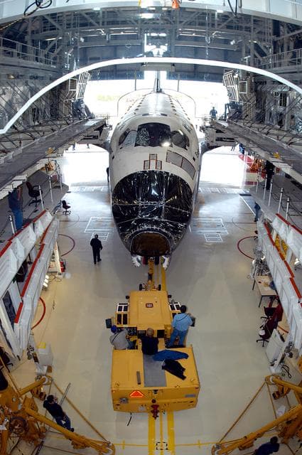 NASA image: KENNEDY SPACE CENTER, FLA. -- Endeavour begins rolling out of the Orbiter Processing Facility for temporary transfer to the Vehicle Assembly Building. The move allows work to be performed in the OPF that can only be accomplished while the bay is empty. Work scheduled in the OPF includes annual validation of the bay’s cranes, work platforms, lifting mechanisms and jack stands. Endeavour will remain in the VAB for approximately 12 days, then return to the OPF.
