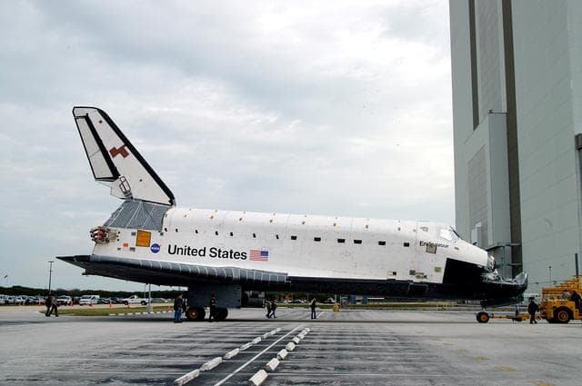NASA image: KENNEDY SPACE CENTER, FLA. -- Endeavour is towed in front of the Vehicle Assembly Building (VAB) where it is going for temporary storage.  The orbiter has been moved from the Orbiter Processing Facility (OPF) to allow work to be performed in the OPF that can only be accomplished while the bay is empty. Work scheduled in the OPF includes annual validation of the bay’s cranes, work platforms, lifting mechanisms and jack stands. Endeavour will remain in the VAB for approximately 12 days, then return to the OPF.
