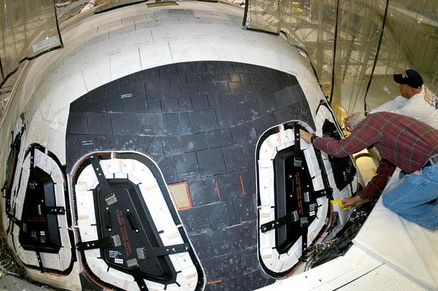 NASA image: KENNEDY SPACE CENTER, FLA. -- At right, Mike Young and Les Hanks, with United Space Alliance, prepare a window on Atlantis for removal.  The windows are being removed to inspect them for contaminants in the thermal seal.  Atlantis has been undergoing routine maintenance in the Orbiter Processing Facility for Return to Flight, on mission STS-114.