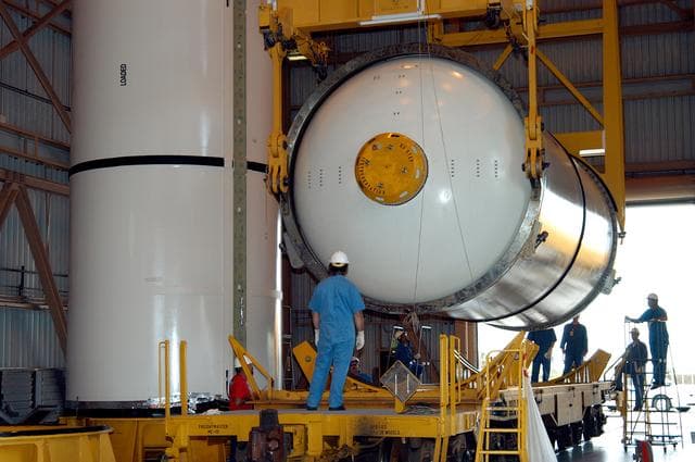 NASA image: KENNEDY SPACE CENTER, FLA. -  In the Rotation Processing and Surge Facility, an SRB solid segment is lowered onto a rail car for shipment to Utah where it will be tested.  The segment was part of the STS-114 stack.  It is the first time actual flight segments that had been stacked for flight in the VAB are being returned to Utah for testing.  It will undergo firing, which will enable inspectors to check the viability of the solid and verify the life expectancy for stacked segments.