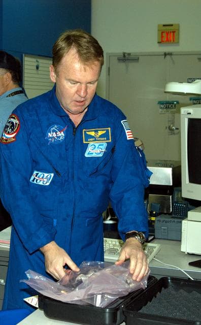 NASA image: KENNEDY SPACE CENTER, FLA. -  STS-114 Mission Specialist Andrew Thomas works on equipment in the Space Station Processing Facility.  He and other crew members are at KSC for equipment familiarization.  STS-114 is classified as Logistics Flight 1 to the International Space Station,  delivering new supplies and replacing one of the orbital outpost’s Control Moment Gyroscopes (CMGs). STS-114 will also carry a Raffaello Multi-Purpose Logistics Module and the External Stowage Platform-2.  The crew is slated to conduct at least three spacewalks: They will demonstrate repair techniques of the Shuttle’s Thermal Protection System,  replace the failed CMG with one delivered by the Shuttle, and  install the External Stowage Platform.