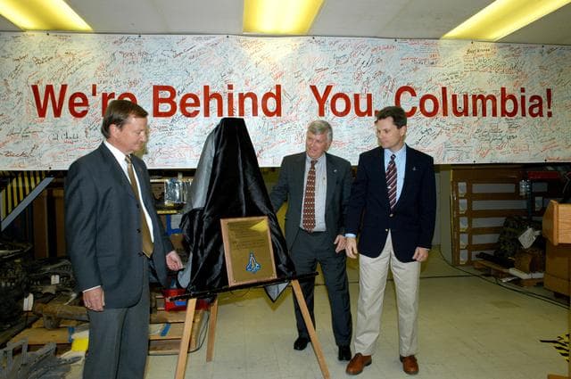 KENNEDY SPACE CENTER, FLA. -  In the Vehicle Assembly Building, Shuttle Launch Director Mike Leinbach, Center Director Jim Kennedy and NASA Vehicle Manager Scott Thurston unveil a plaque honoring “Columbia, the crew of STS-107, and their loved ones.”  The site is the “Columbia room,” a permanent repository of the debris collected in the aftermath of the tragic accident Feb. 1, 2003, that claimed the orbiter and lives of the seven-member crew.  The dedication of the plaque was made in front of the 40-member preservation team.