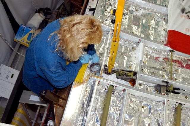 NASA image: KENNEDY SPACE CENTER, FLA. -  A worker in the Orbiter Processing Facility checks part of the payload bay on Discovery.  The orbiter recently underwent an Orbiter Major Modification period, which included inspection, modifications and reservicing of most systems onboard. The work on Discovery also included the installation of a Multifunction Electronic Display Subsystem (MEDS) - a state-of-the-art “glass cockpit.”  The orbiter is now being prepared for eventual launch on a future mission.