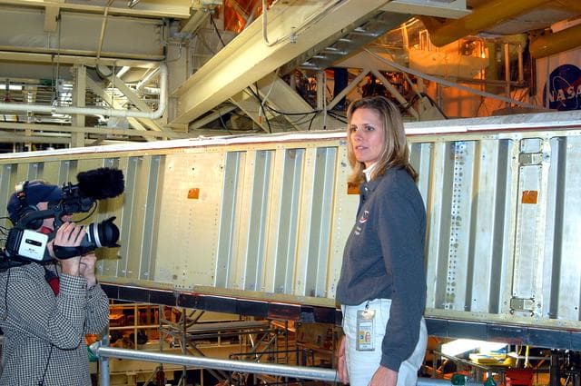 NASA image: KENNEDY SPACE CENTER, FLA. -  In the Orbiter Processing Facility, Stephanie Stilson, NASA vehicle manager for Discovery, stands in front of a leading edge on the wing of Discovery.  She is being filmed for a special feature on the KSC Web about the recent Orbiter Major Modification period on Discovery, which included inspection, modifications and reservicing of most systems onboard, plus installation of a Multifunction Electronic Display Subsystem (MEDS) - a state-of-the-art “glass cockpit.”  The orbiter is now being prepared for eventual launch on a future mission.