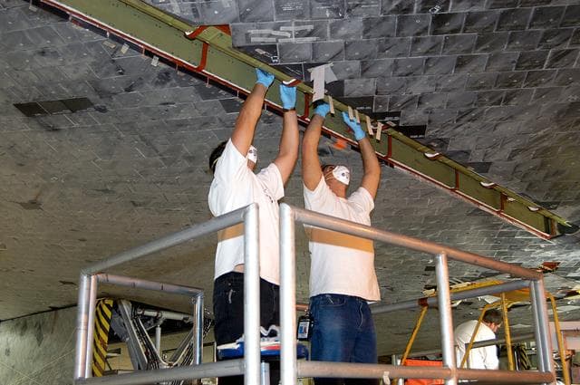 NASA image: KENNEDY SPACE CENTER, FLA. -  In the Orbiter Processing Facility, technicians work on insulation tiles near the landing gear door of orbiter Discovery.  The orbiter is now being prepared for eventual launch on a future mission.