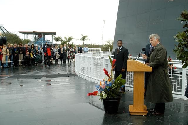 NASA image: KENNEDY SPACE CENTER, FLA. -  Center Director Jim Kennedy (right) speaks to attendees at a memorial service honoring the crew of Columbia.  Behind him are KSC Deputy Director Woodrow Whitlow Jr. and Executive Director of Florida Space Authority Winston Scott, who is a former astronaut who flew on Columbia in 1997. They are standing in front of the Space Memorial Mirror at the KSC Visitor Complex.  Attended by many friends, co-workers and families, the memorial service was also open to the public, some of whom are seen at left.  Feb. 1 is the one-year anniversary of the loss of the crew and orbiter Columbia in a tragic accident as the ship returned to Earth following mission STS-107.