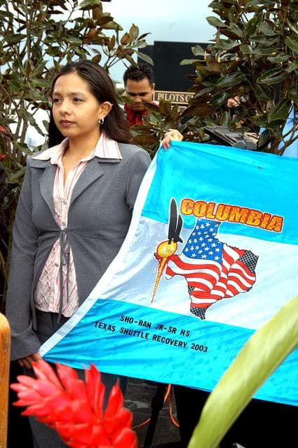 NASA image: KENNEDY SPACE CENTER, FLA. - A student from Shoshone-Bannock Junior-Senior High School, Fort Hall, Idaho, holds part of a flag presented by dancers from the Shoshone-Bannock Native American community, Fort Hall, Idaho, commemorating the orbiter Columbia and her crew.  The dancers performed a healing ceremony during the memorial service held at the Space Memorial Mirror for the crew of Columbia.  Feb. 1 is the one-year anniversary of the loss of the crew and orbiter Columbia in a tragic accident as the ship returned to Earth following mission STS-107.  Students and staff of the Shoshone-Bannock Nation had an experiment on board Columbia. The public was invited to the memorial service, held in the KSC Visitor Complex, which included comments by Center Director Jim Kennedy and Executive Director of Florida Space Authority Winston Scott.  Scott is a former astronaut who flew on Columbia in 1997.