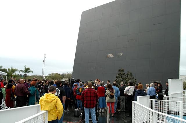 NASA image: KENNEDY SPACE CENTER, FLA. - At the Space Memorial Mirror in the KSC Visitor Complex, visitors gather around dancers from the Shoshone-Bannock Native American community, Fort Hall, Idaho, who are performing a healing ceremony during the memorial service held for the crew of Columbia.  Feb. 1 is the one-year anniversary of the loss of the crew and orbiter Columbia in a tragic accident as the ship returned to Earth following mission STS-107.  Students and staff of the Shoshone-Bannock Nation had an experiment on board Columbia. The public was invited to the memorial service, held in the KSC Visitor Complex, which included comments by Center Director Jim Kennedy and Executive Director of Florida Space Authority Winston Scott.  Scott is a former astronaut who flew on Columbia in 1997.