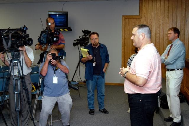 NASA image: KENNEDY SPACE CENTER, FLA. - Armando Oliu, Final Inspection Team lead for the Shuttle program, speaks to reporters about the aid the Image Analysis Lab is giving the FBI in a kidnapping case.  Behind him at right is Mike Rein, External Affairs division chief.  Oliu oversees the image lab that is using an advanced SGI® TP9500 data management system to review the tape of the kidnapping in progress in Sarasota, Fla.  KSC installed the new $3.2 million system in preparation for Return to Flight of the Space Shuttle fleet.  The lab is studying the Sarasota kidnapping video to provide any new information possible to law enforcement officers.  KSC is joining NASA’s Marshall Space Flight Center in Alabama in reviewing the tape.