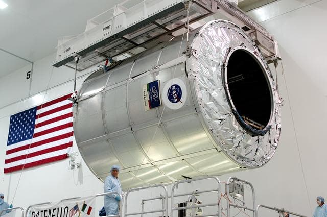 NASA image: KENNEDY SPACE CENTER, FLA. - The Multi-Purpose Logistics Module Raffaello is lifted from its stand in the Space Station Processing Facility to move to another work stand.  Raffaello is the second MPLM built by the Italian Space Agency, serving as a reusable logistics carrier and primary delivery system to resupply and return station cargo requiring a pressurized environment.  It is being moved to allow the third MPLM, Donatello, to be brought in for routine testing.  Donatello has been stored in the Operations and Checkout Building.  This is the first time all three MPLMs are in the SSPF; the other one is the Leonardo.  Raffaello is scheduled to fly on Space Shuttle Atlantis on mission STS-114.