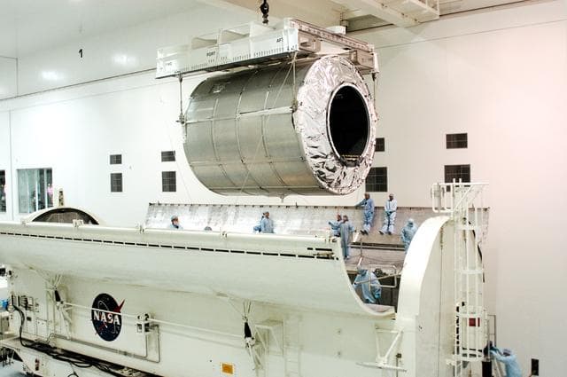 NASA image: KENNEDY SPACE CENTER, FLA. - The Multi-Purpose Logistics Module Donatello is suspended by cables over the payload canister in the Space Station Processing Facility.  Previously housed in the Operations and Checkout Building, Donatello was brought into the SSPF for routine testing.  This is the first time all three MPLMs (Donatello, Raffaello and Leonardo) are in the SSPF.  The MPLMs were built by the Italian Space Agency, to serve as reusable logistics carriers and the primary delivery system to resupply and return station cargo requiring a pressurized environment.  The third MPLM, Raffaello is scheduled to fly on Space Shuttle Atlantis on mission STS-114.