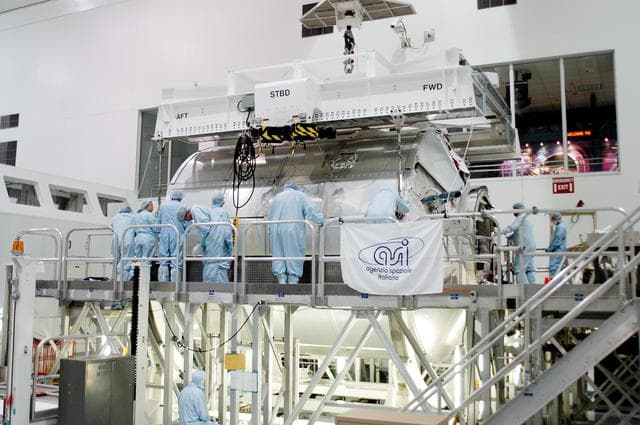 NASA image: KENNEDY SPACE CENTER, FLA. - In the Space Station Processing Facility,  workers confirm the Multi-Purpose Logistics Module Donatello is safely in place on a work stand.  Previously housed in the Operations and Checkout Building, Donatello was brought into the SSPF for routine testing.  This is the first time all three MPLMs (Donatello, Raffaello and Leonardo) are in the SSPF.  The MPLMs were built by the Italian Space Agency, to serve as reusable logistics carriers and the primary delivery system to resupply and return station cargo requiring a pressurized environment.  The third MPLM, Raffaello, is scheduled to fly on Space Shuttle Atlantis on mission STS-114.