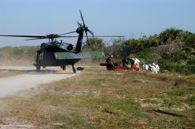 NASA image: KENNEDY SPACE CENTER, FLA. - In a “Mode VII” emergency landing simulation at Kennedy Space Center, a helicopter crew helps “rescued” astronauts.  The purpose of Mode VII is to exercise emergency preparedness personnel, equipment and facilities in rescuing astronauts from a downed orbiter and providing immediate medical attention.  This simulation presents an orbiter that has crashed short of the Shuttle Landing Facility in a wooded area 2-1/2 miles south of Runway 33.  Emergency crews are responding to the volunteer “astronauts” simulating various injuries inside an orbiter crew compartment mock-up.  Rescuers must remove the crew, provide triage and transport to hospitals those who need further treatment.  Local hospitals are participating in the exercise.