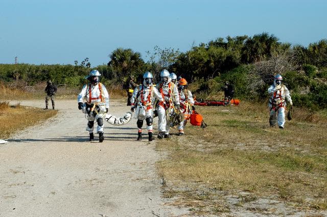 NASA image: KENNEDY SPACE CENTER, FLA. - Emergency crews leave the scene after a helicopter removed “rescued” astronauts from the scene.  They are taking part in a “Mode VII” emergency landing simulation at Kennedy Space Center, in order to exercise emergency preparedness personnel, equipment and facilities in rescuing astronauts from a downed orbiter and providing immediate medical attention.  This simulation presents an orbiter that has crashed short of the Shuttle Landing Facility in a wooded area 2-1/2 miles south of Runway 33.  Emergency crews are responding to the volunteer “astronauts” simulating various injuries inside an orbiter crew compartment mock-up.  Rescuers must remove the crew, provide triage and transport to hospitals those who need further treatment.  Local hospitals are participating in the exercise.