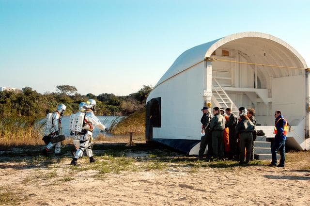NASA image: KENNEDY SPACE CENTER, FLA. - Emergency crew members return to the orbiter crew compartment mock-up that is the scene of a “Mode VII” emergency landing simulation at Kennedy Space Center.  The purpose of the Mode VII is to exercise emergency preparedness personnel, equipment and facilities in rescuing astronauts from a downed orbiter and providing immediate medical attention.  This simulation presents an orbiter that has crashed short of the Shuttle Landing Facility in a wooded area 2-1/2 miles south of Runway 33.  Emergency crews are responding to the volunteer “astronauts” simulating various injuries inside the mock-up compartment.  Rescuers have had to remove the crew, provide triage and transport to hospitals those who need further treatment.  Local hospitals are participating in the exercise.