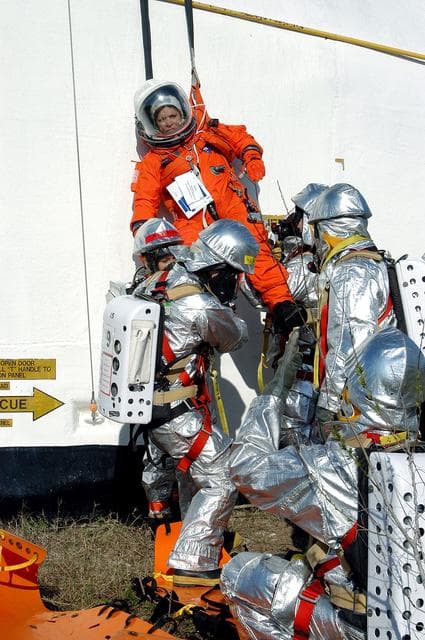 NASA image: KENNEDY SPACE CENTER, FLA. - Emergency crew members on the ground take hold of a volunteer “astronaut” lowered from the top of the orbiter crew compartment mock-up that is the scene of a “Mode VII” emergency landing simulation at Kennedy Space Center.  The purpose of the Mode VII is to exercise emergency preparedness personnel, equipment and facilities in rescuing astronauts from a downed orbiter and providing immediate medical attention.  This simulation presents an orbiter that has crashed short of the Shuttle Landing Facility in a wooded area 2-1/2 miles south of Runway 33.  Emergency crews are responding to the volunteer astronauts who are simulating various injuries.  Rescuers must remove the crew, provide triage and transport to hospitals those who need further treatment.  Local hospitals are participating in the exercise.
